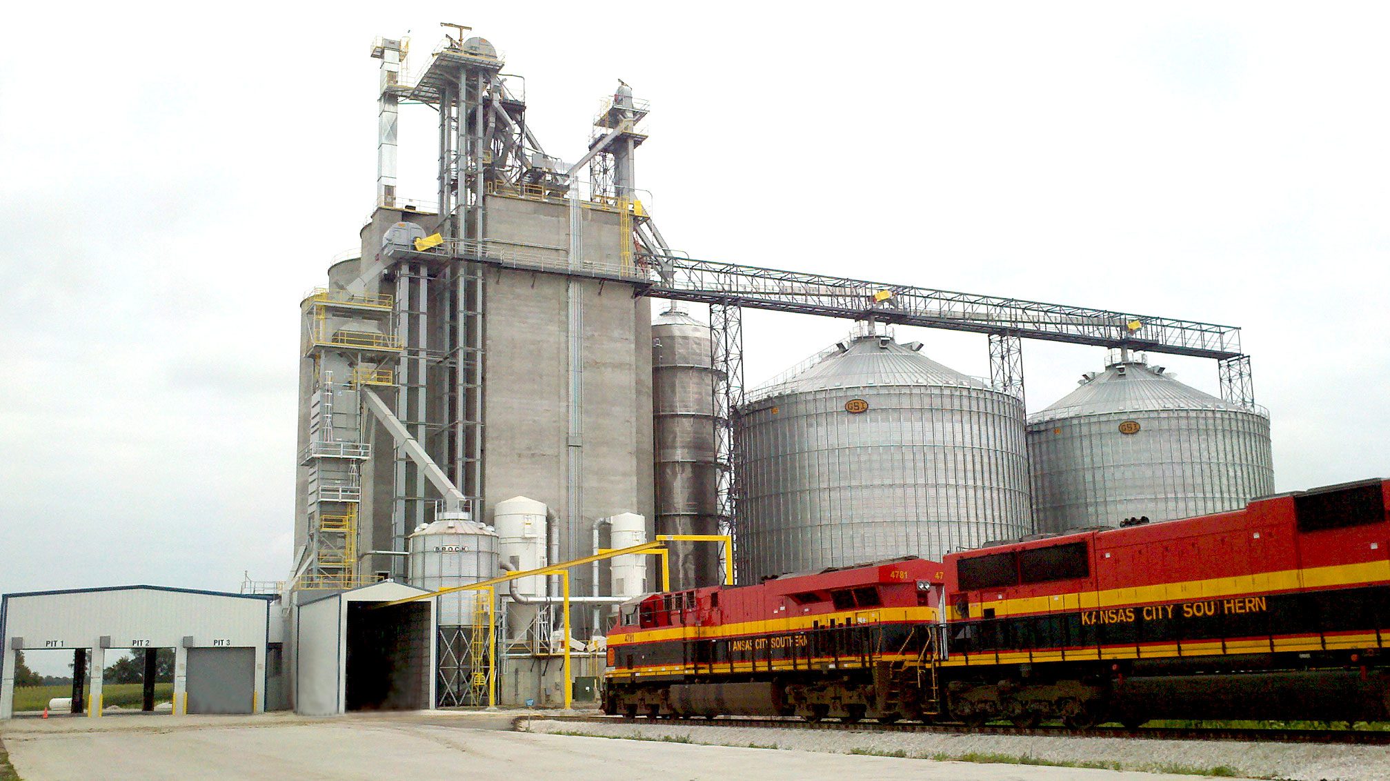 Train passing by large grain silos