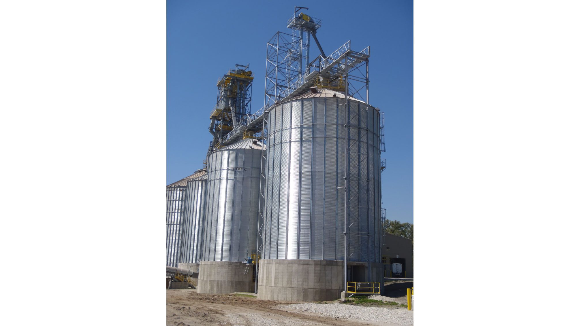 Large metal grain silos under clear sky