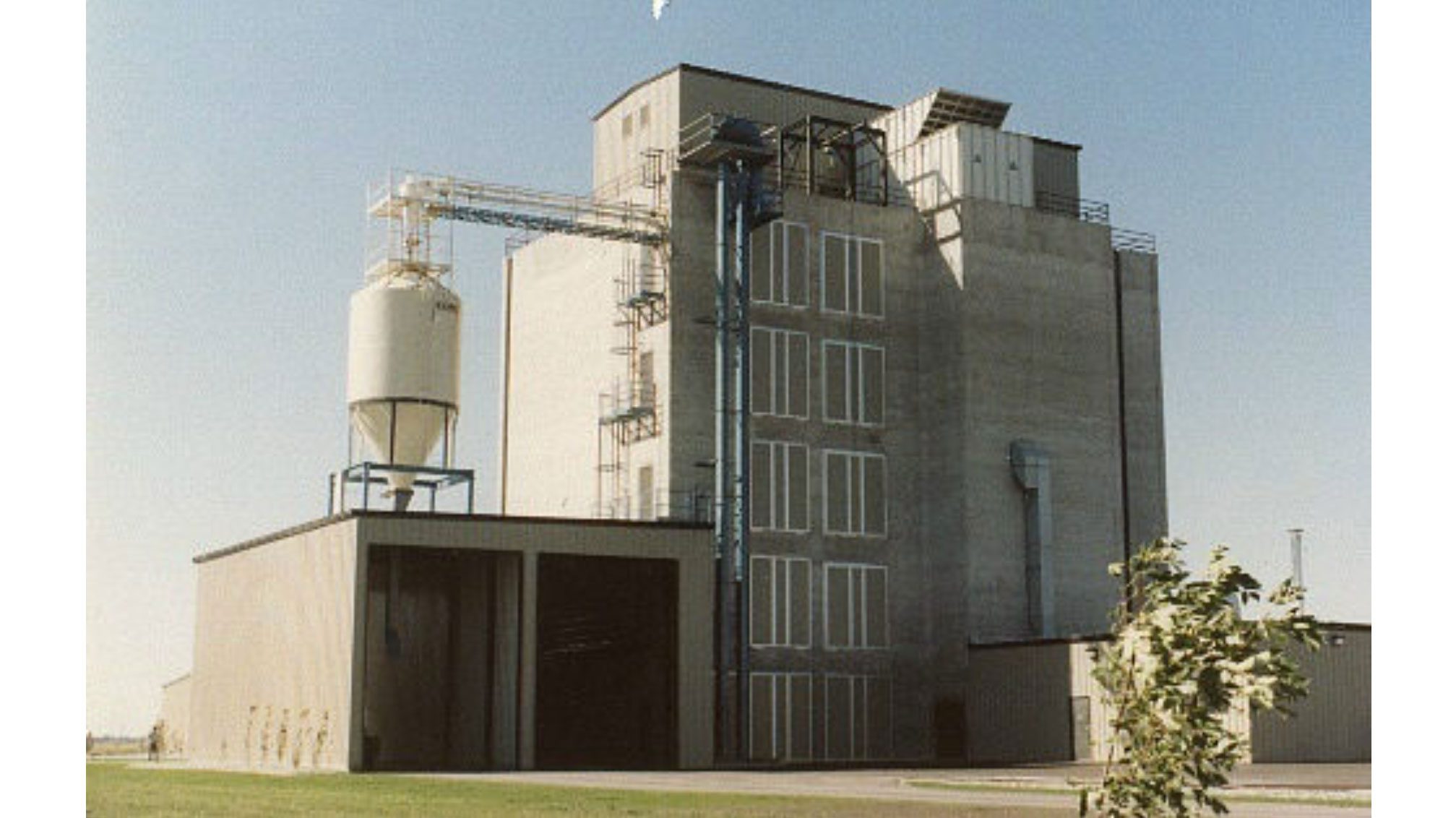 Industrial building with silo and blue sky.