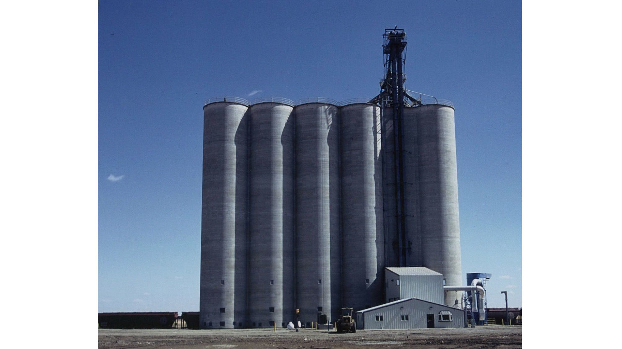 Large concrete silos with small building.